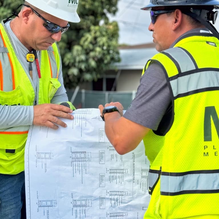 2 men in MCI gear going over blueprints