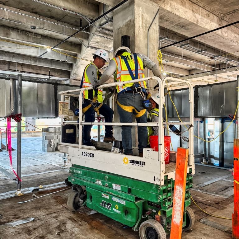 2 menu standing in a cherry picker in a concrete structure